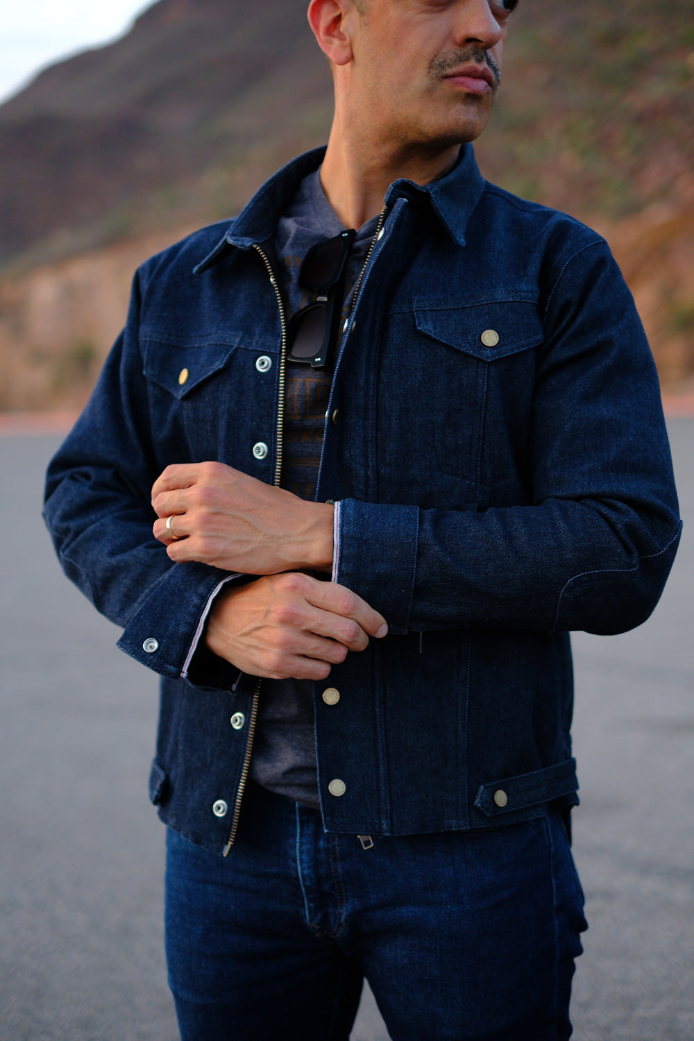 Man wearing a dark blue denim jacket with a mountainous background