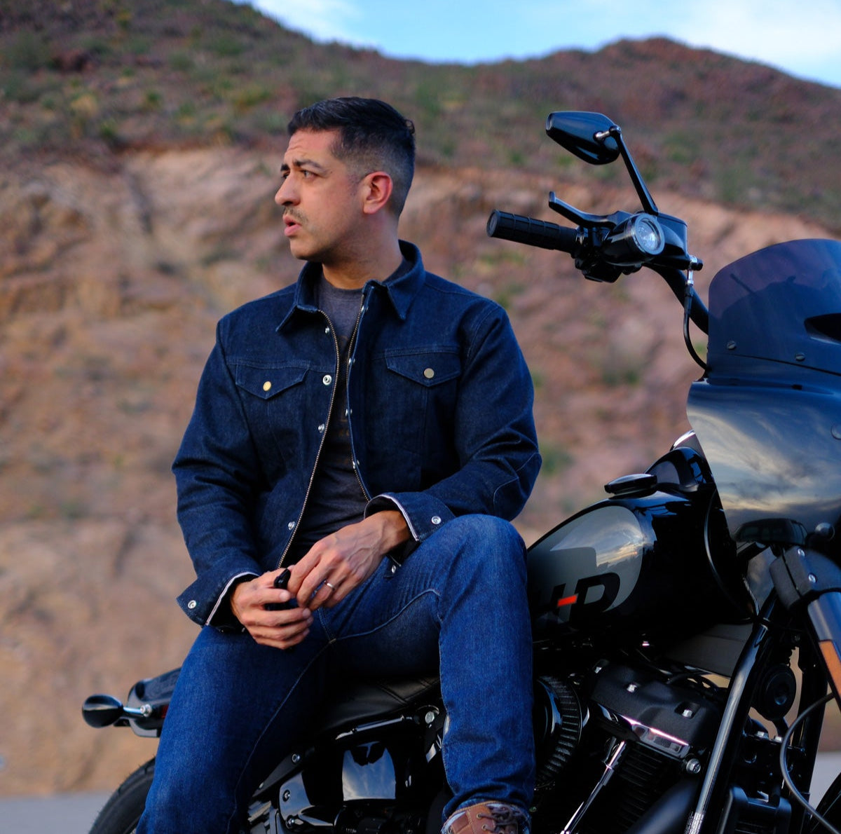 Man sitting on a motorcycle with a mountainous background